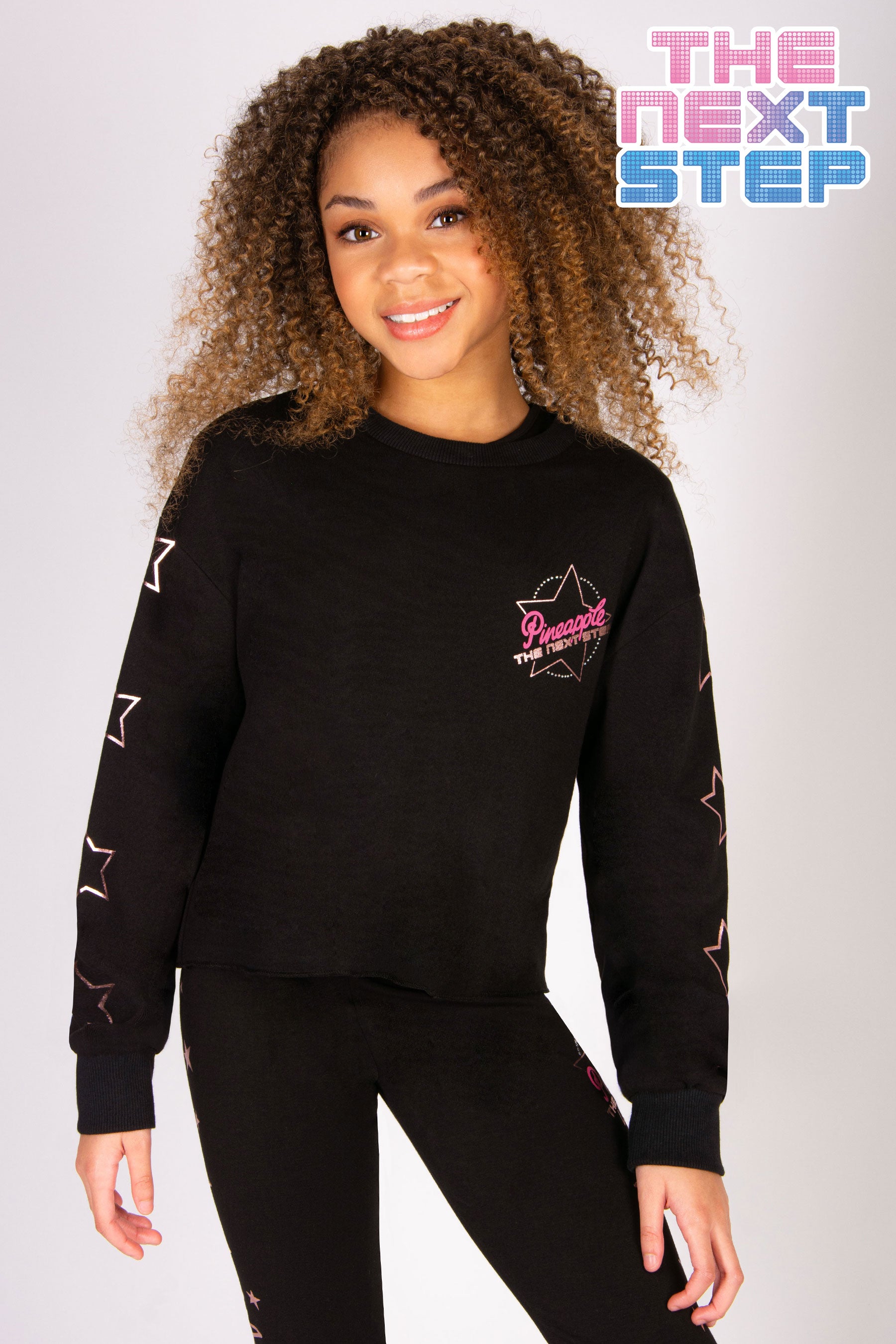 Girls' black crewneck jumper with a small The Next Step logo and stars along the sleeves.