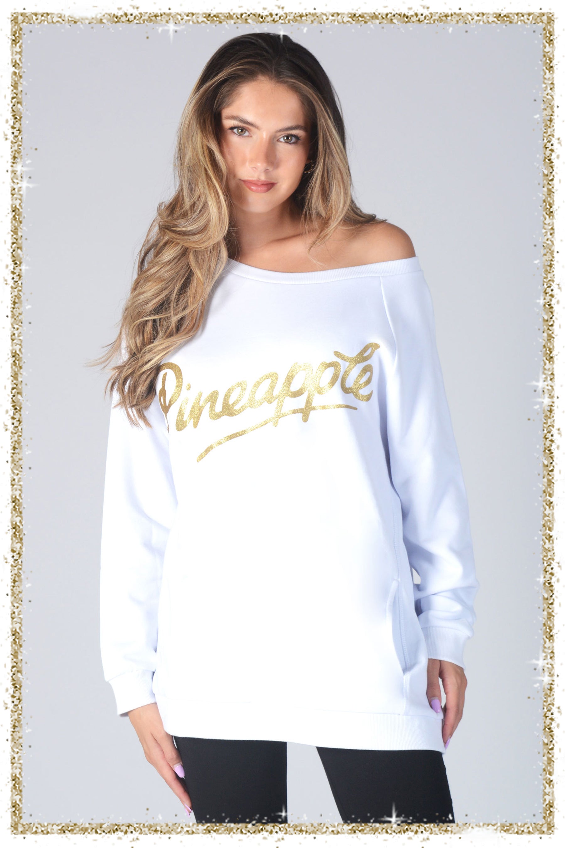 Woman wearing a white sweatshirt with 'Pineapple' printed in gold on a plain background