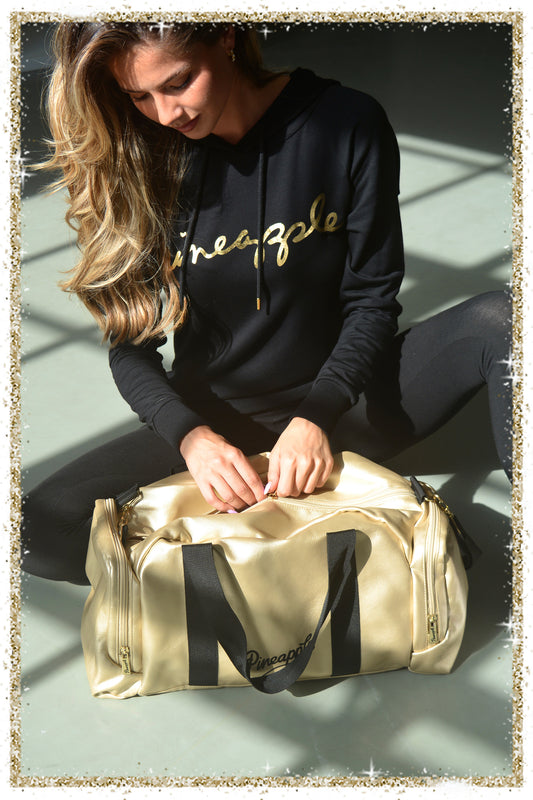 Woman sitting on the floor with a gold duffel bag