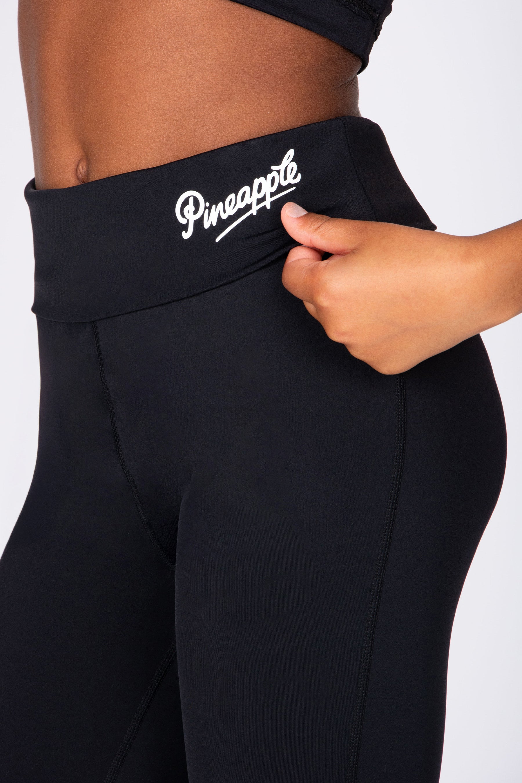 Black active trousers with 'Pineapple' branding on a white background