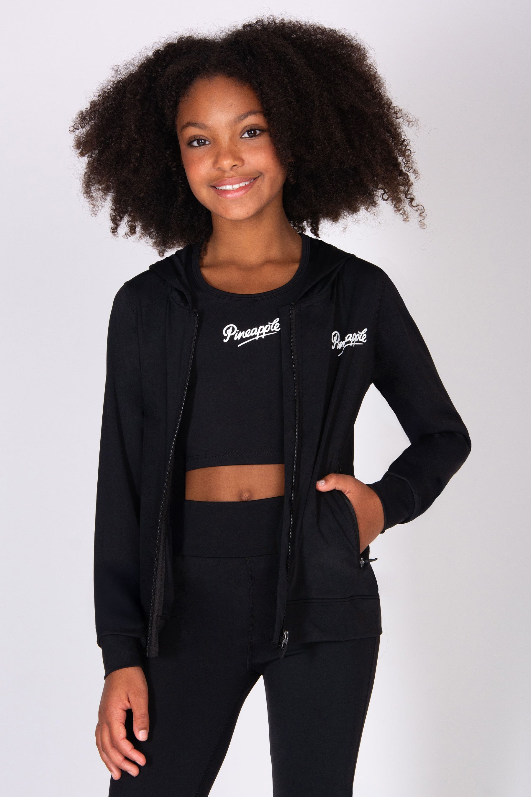 Girl wearing a black hoodie and trousers on a white background