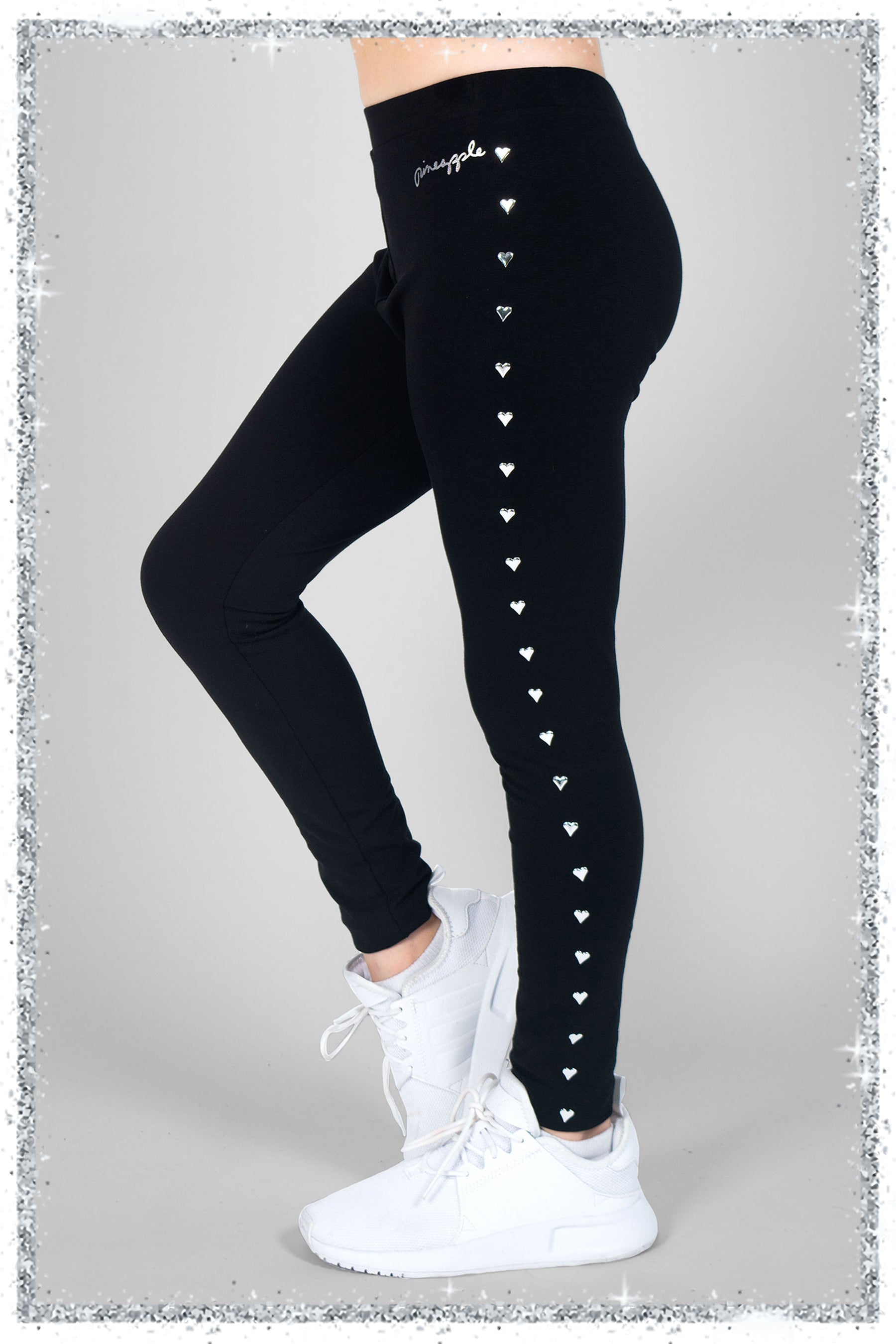 Black leggings with heart studs worn by a person on a gray background