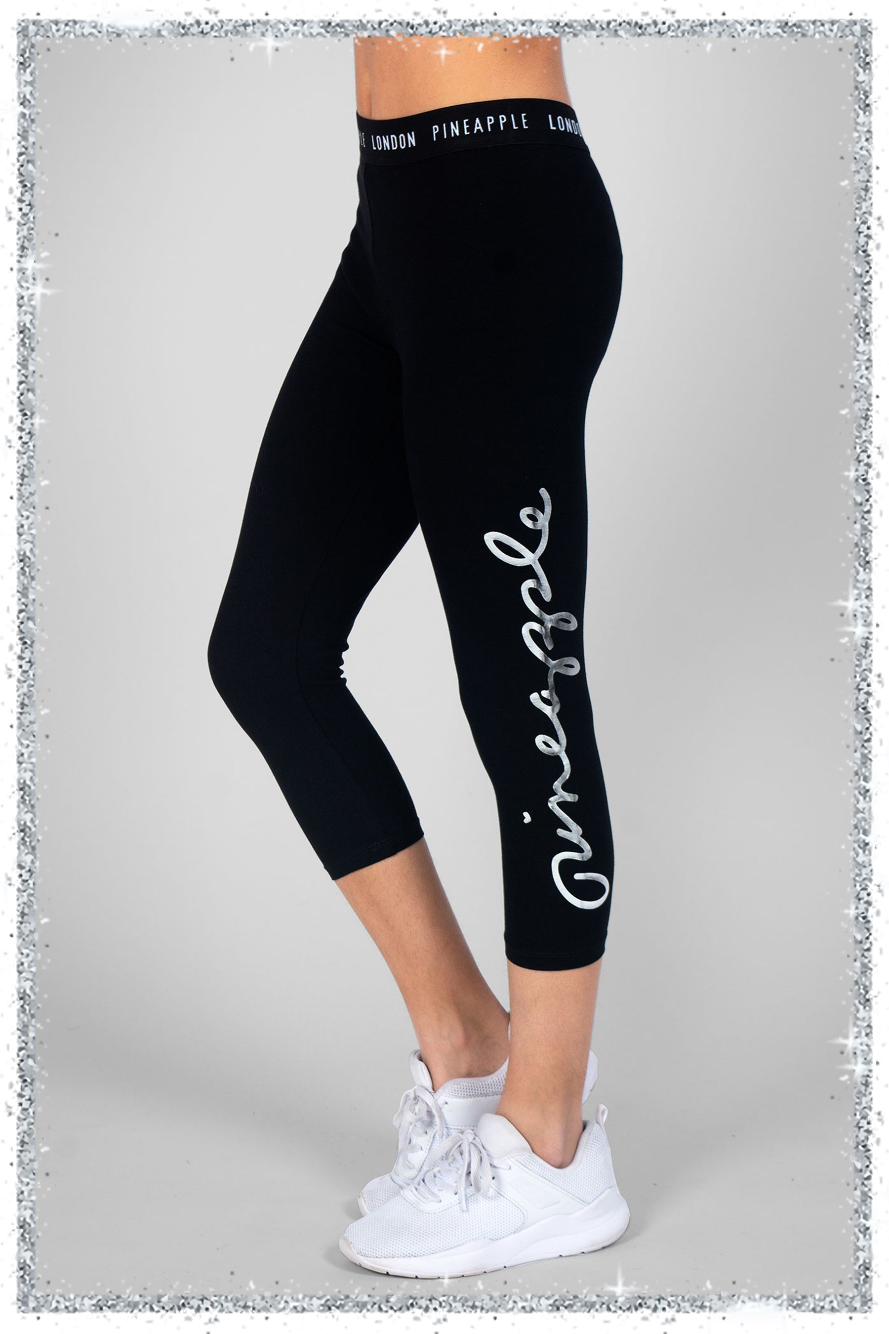 Black leggings with 'Pineapple' silver foil branding on a grey background