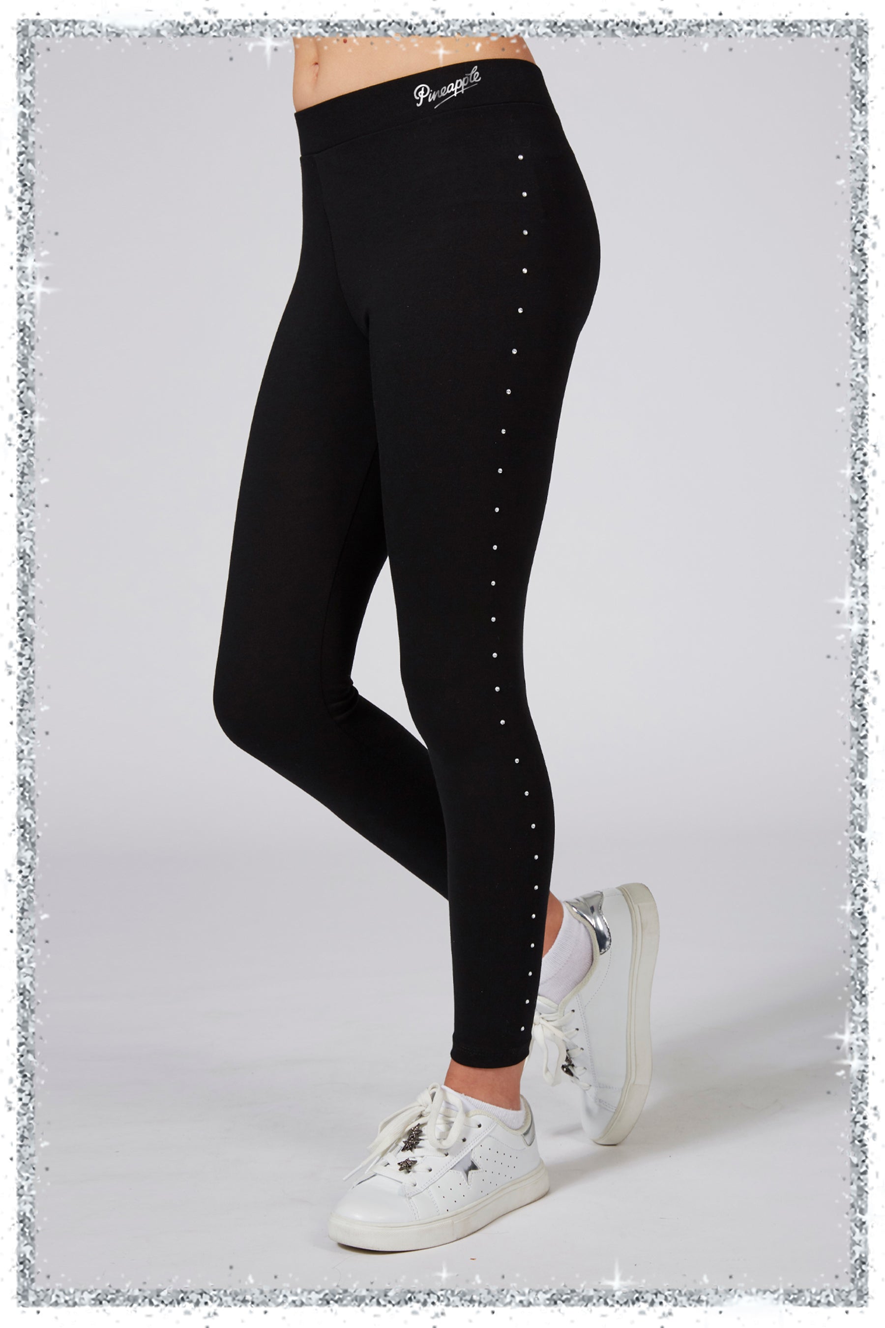 Black leggings with white embellishments worn by a person on a light gray background