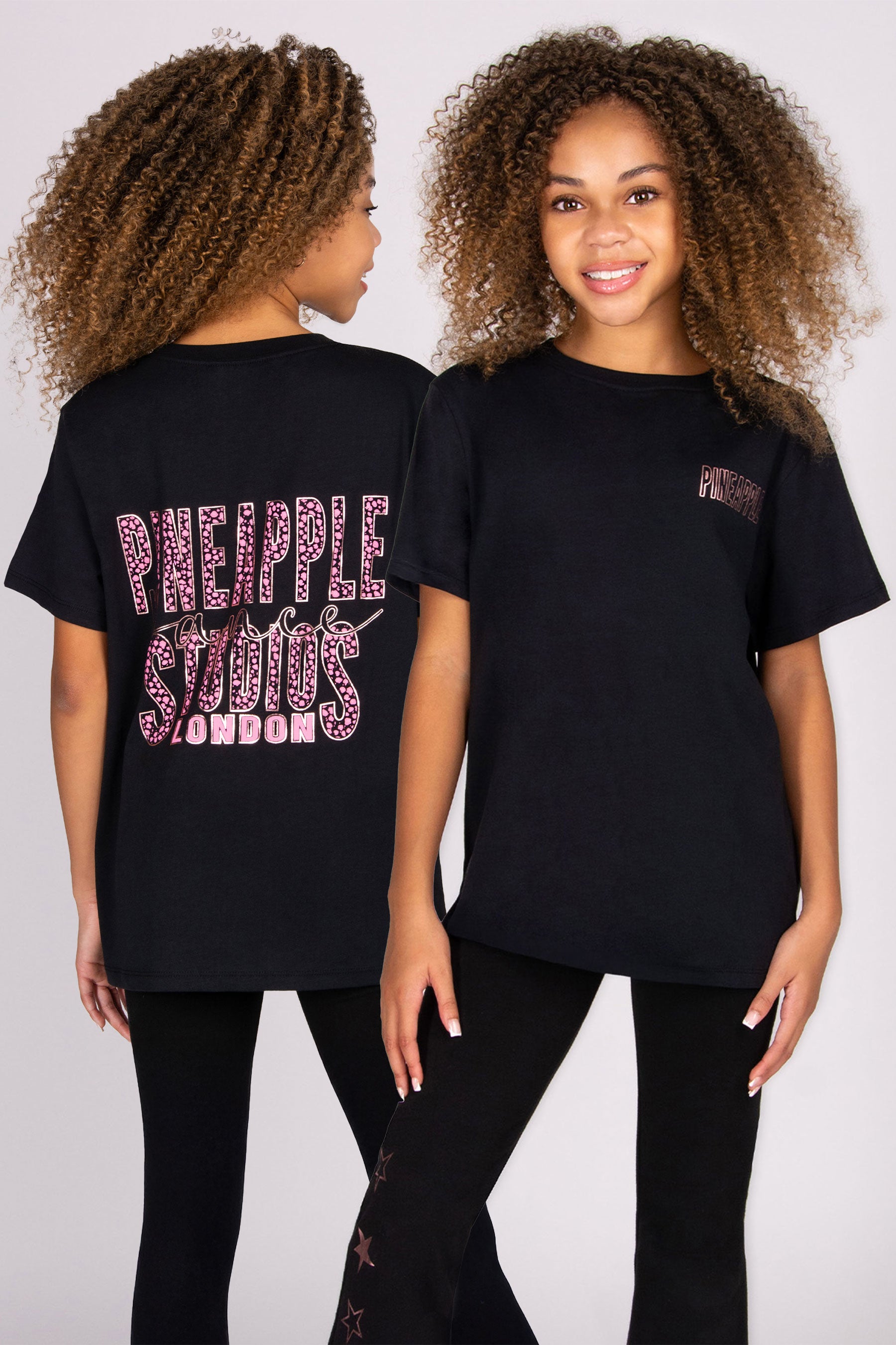 Girls wearing black t-shirt with 'Pineapple Studios London' text on the back on a white background