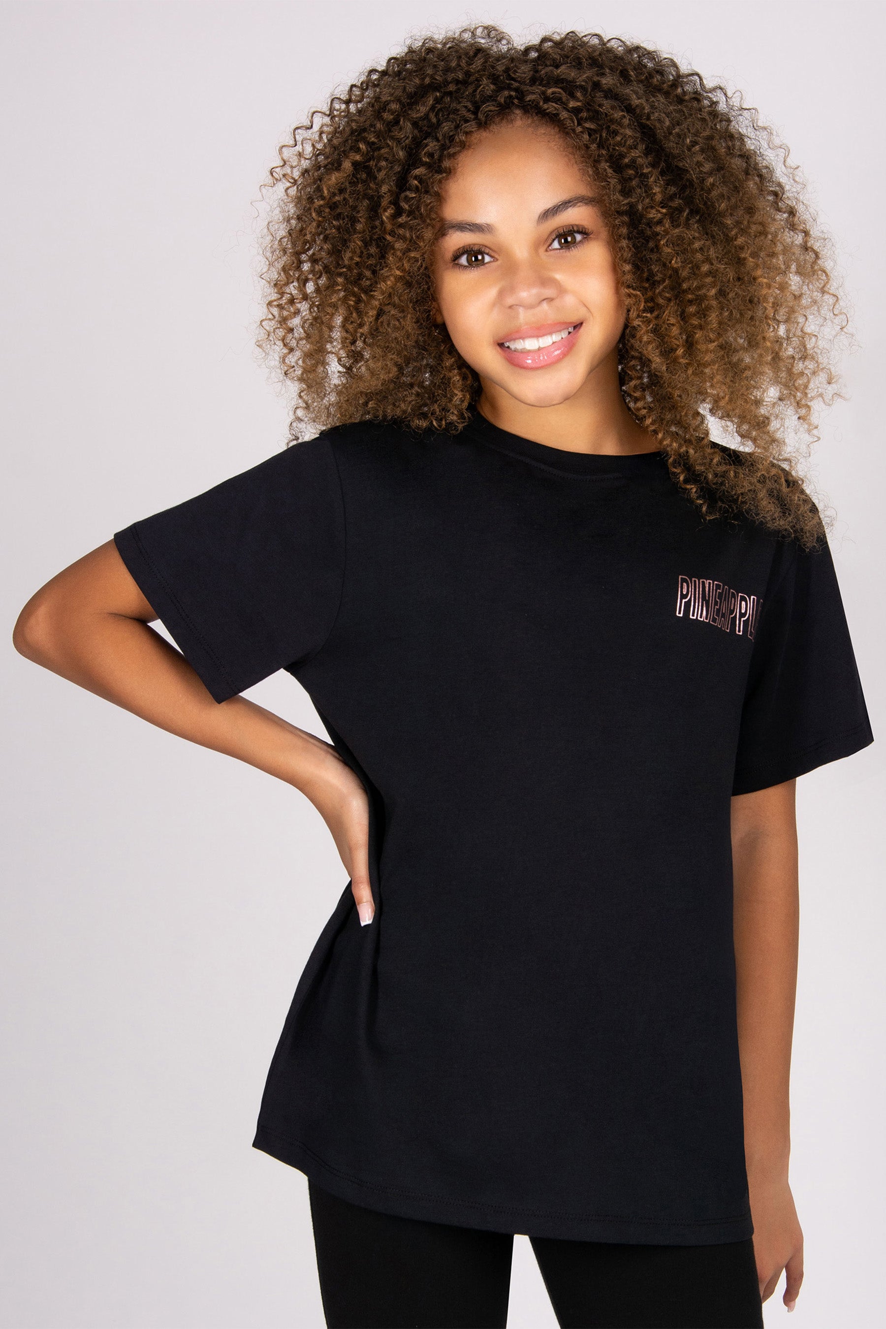 Person wearing a black t-shirt with a logo on a plain background