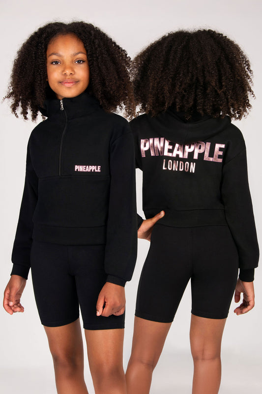 Black hoodie and shorts set with 'Pineapple London' branding worn by a model on a white background