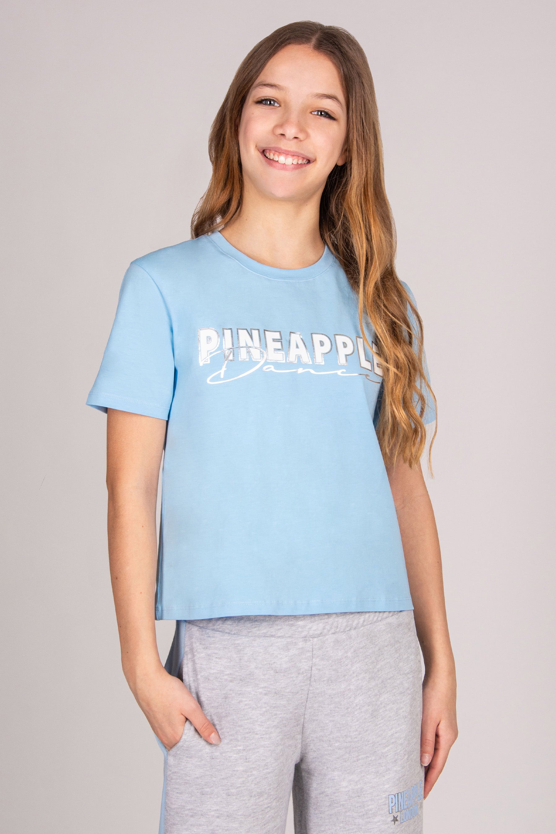 Girl wearing a regular fit blue t-shirt against a plain background.