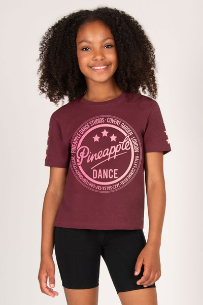 Young girl wearing a maroon t-shirt with 'Pineapple Dance' logo on a white background