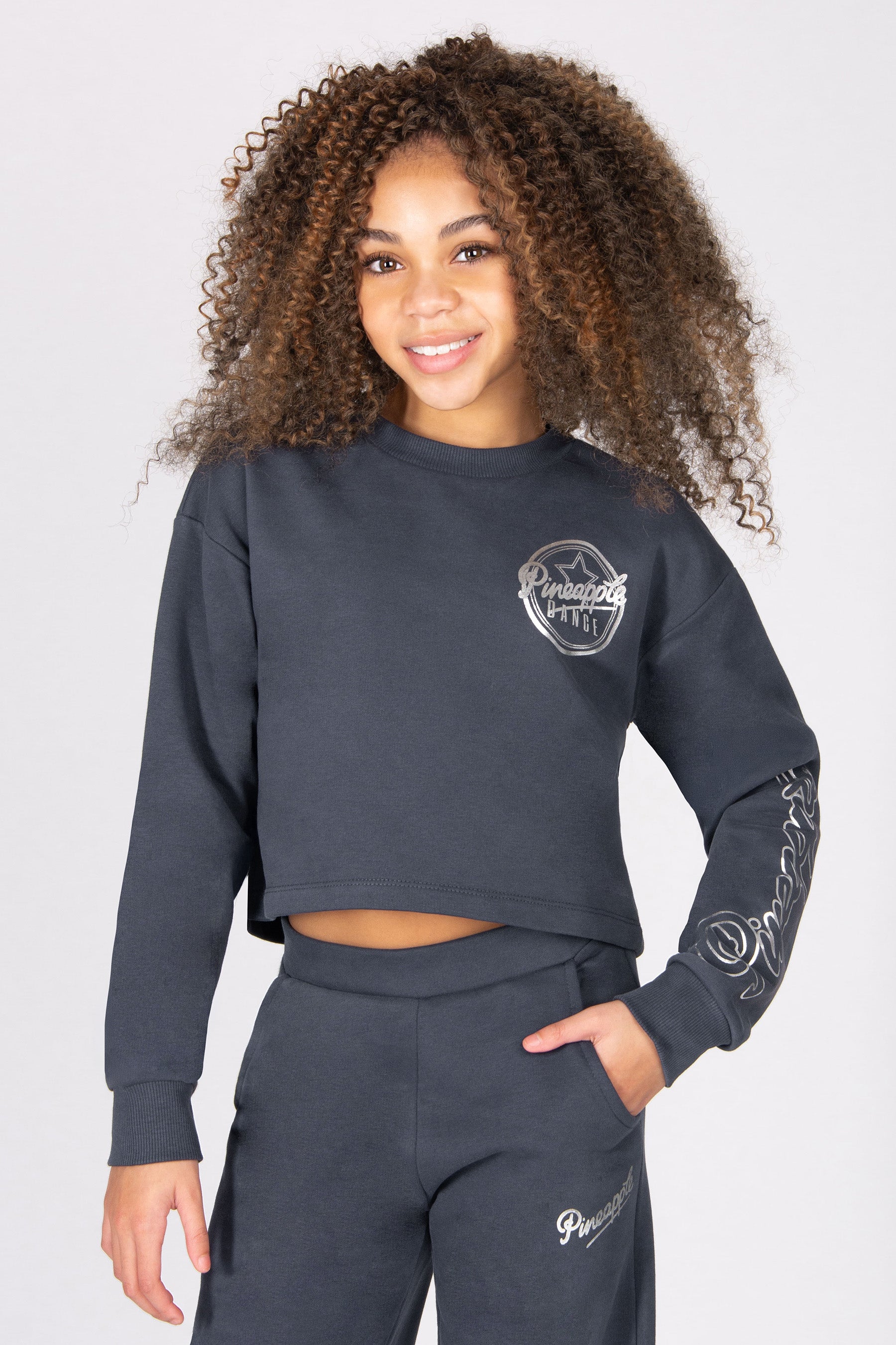 Girl wearing a grey sweatshirt and trousers on a light grey background