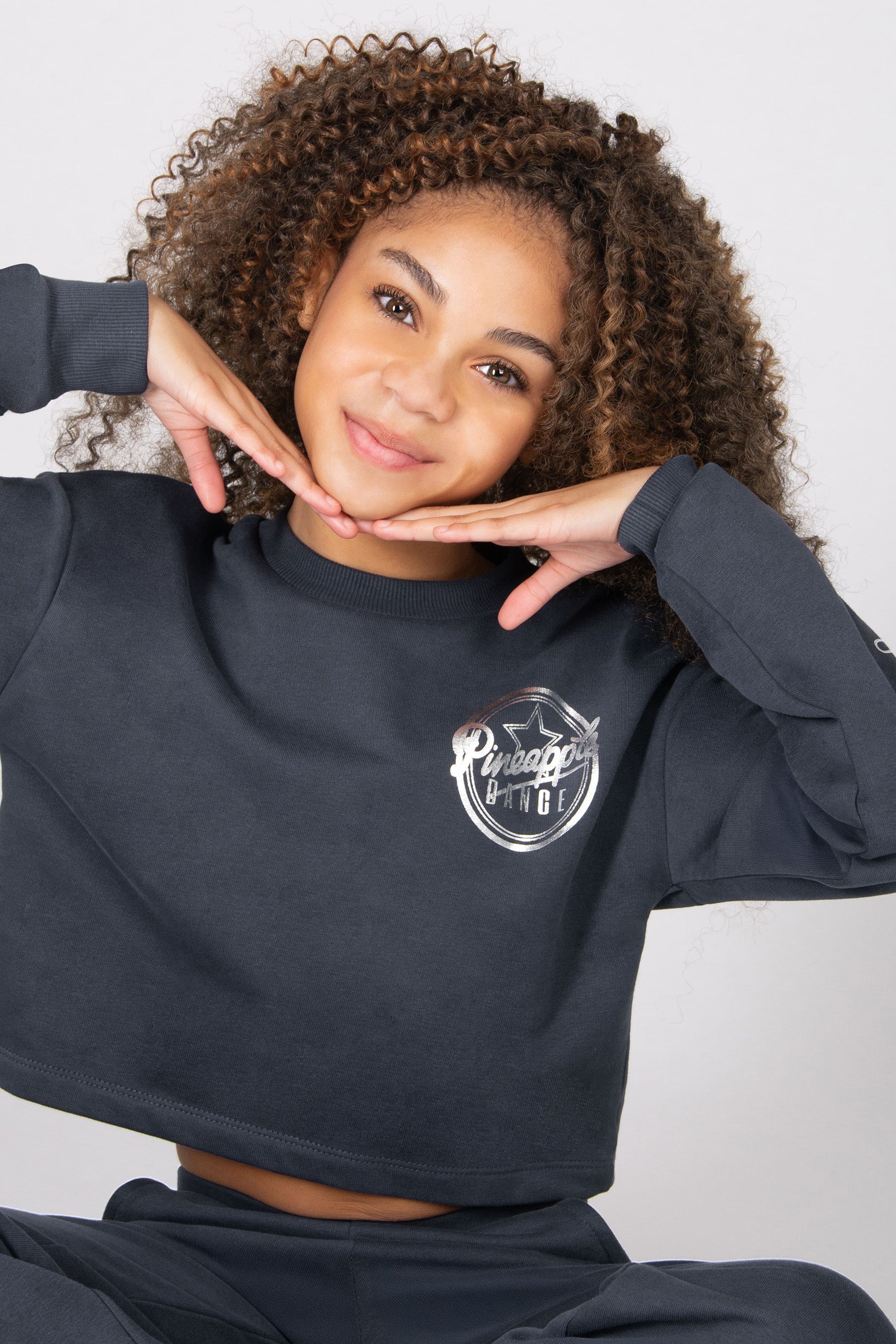 Girls wearing a grey sweatshirt with a logo on a white background