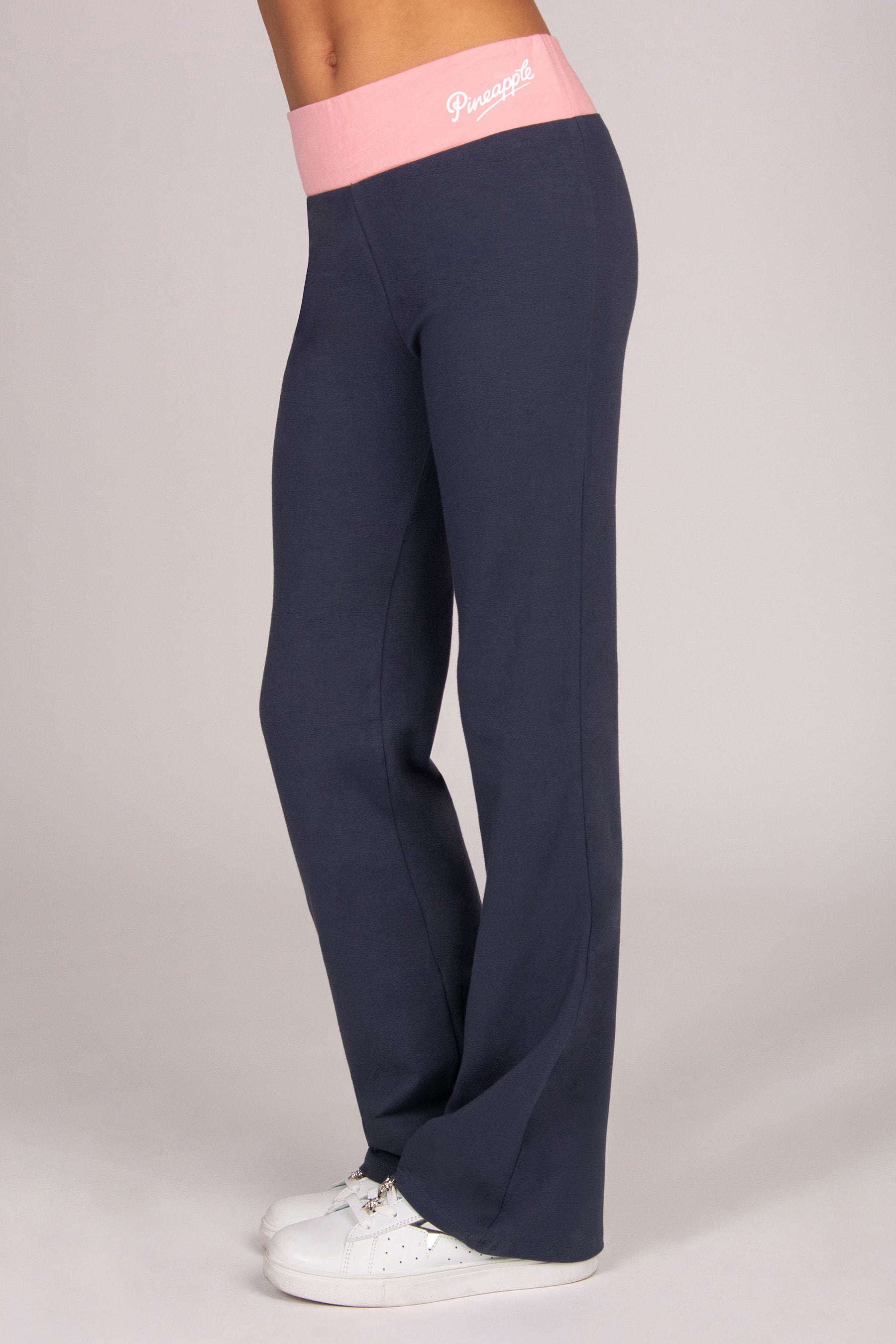 Dark grey flared trousers with light pink waistband on a light background.