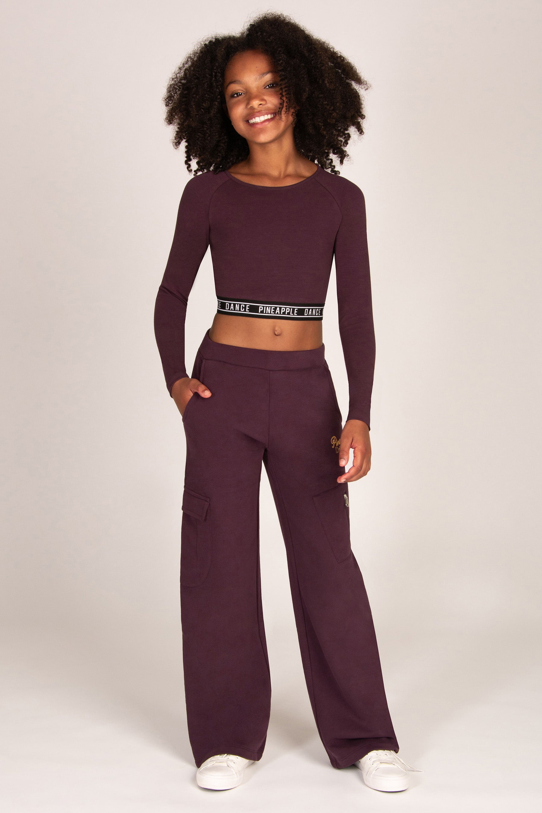 Girl wearing a maroon brown wide-leg trousers with matching long-sleeve top on a white background