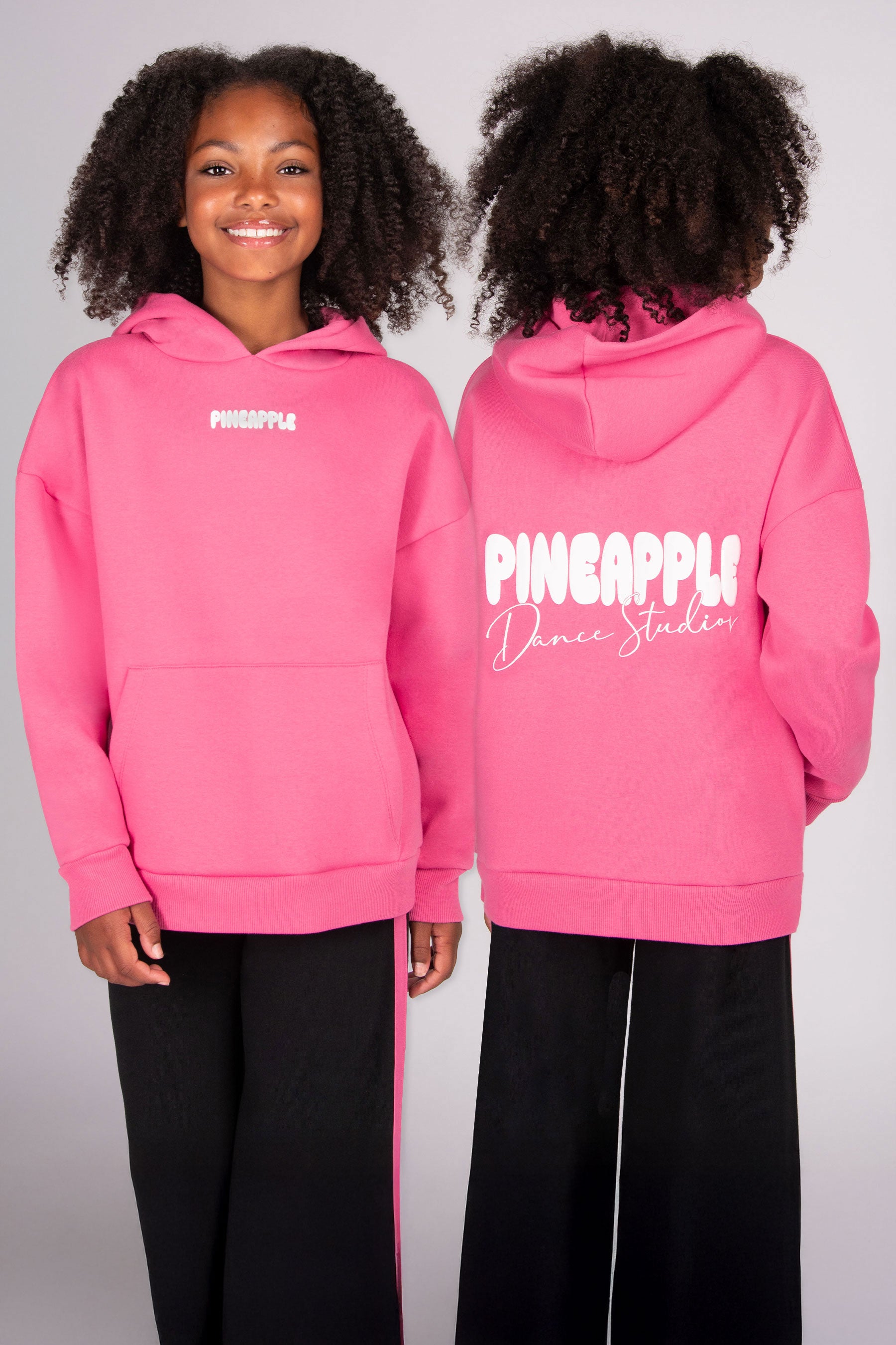 Pink hoodie with 'Pineapple Dance Studios' back print worn by a girl, showing front and back views.