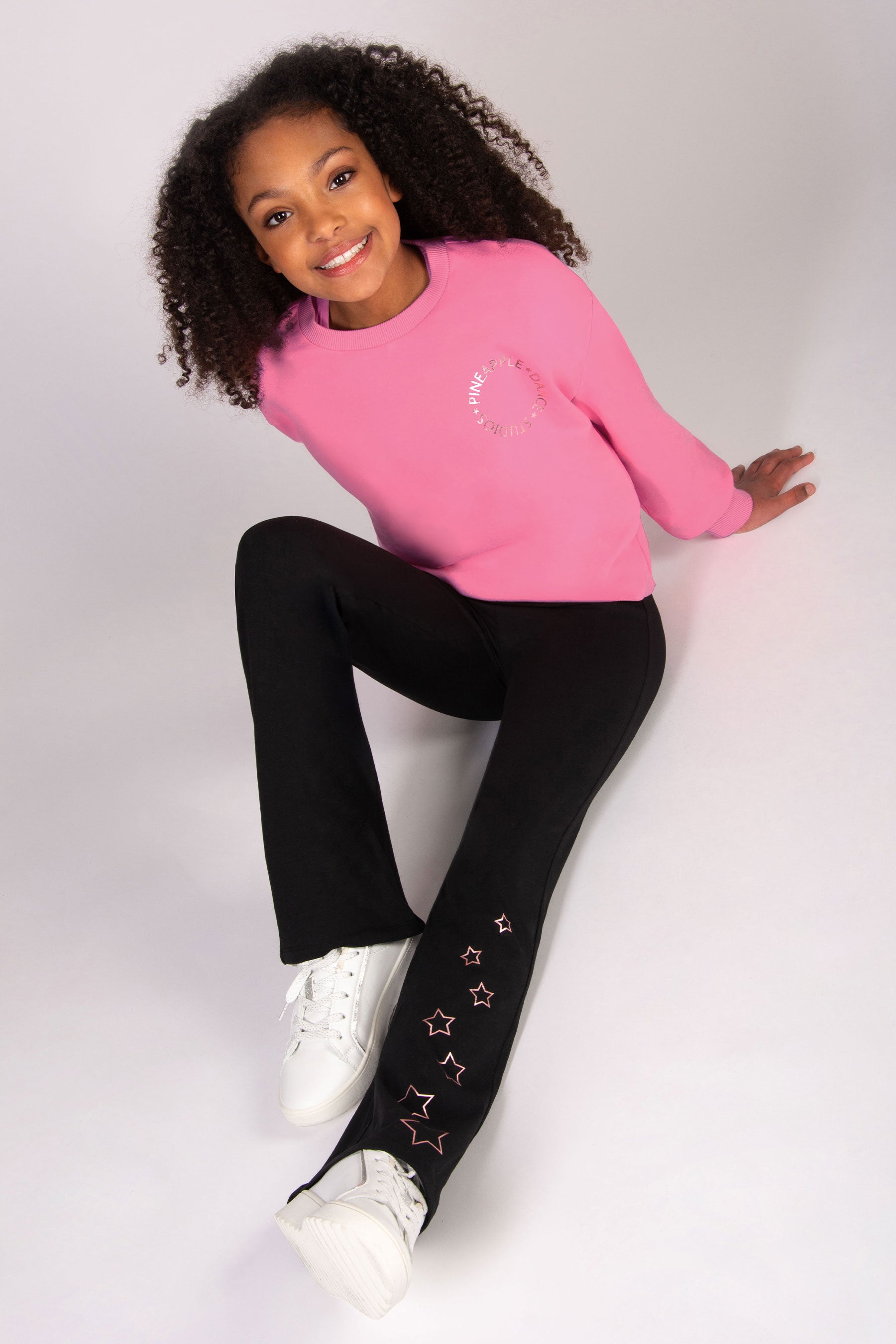 girl wearing black flared trousers and matching pink sweatshirt