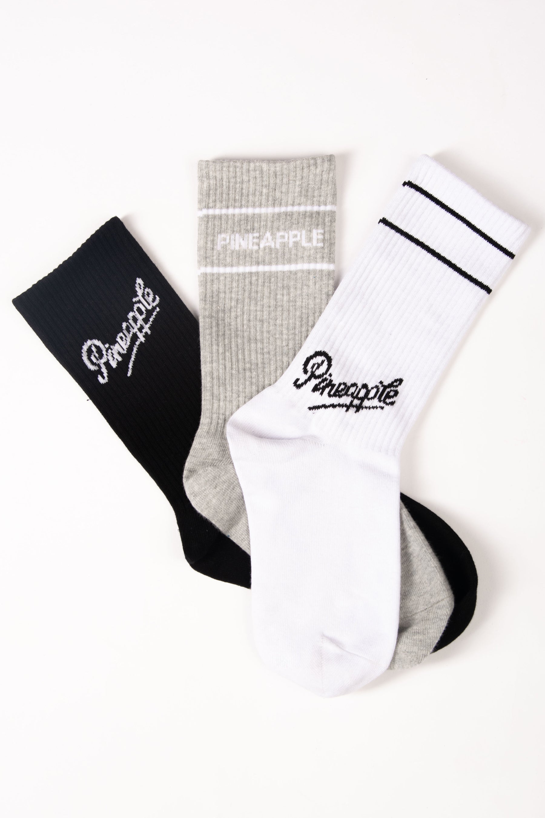 Three socks in black, gray, and white with 'Pineapple' branding on a white background