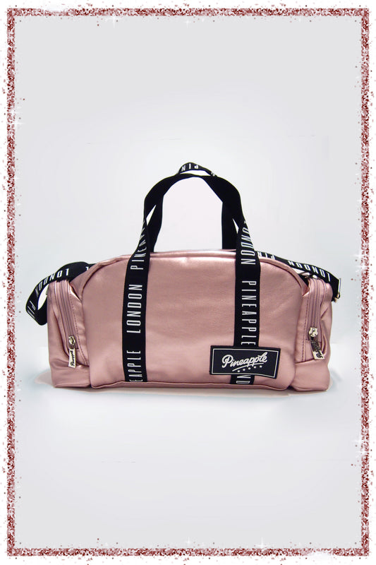 Pink duffel bag with black straps and a brand label on a white background