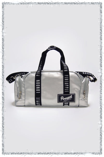 Silver duffel bag with black straps and a brand logo on a light gray background