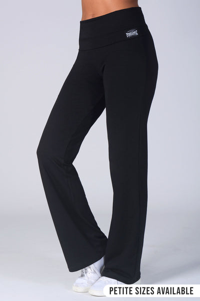 Black high-waisted yoga pants with a small white logo on the left hip, shown on a model from the waist down wearing white sneakers against a light gray background.