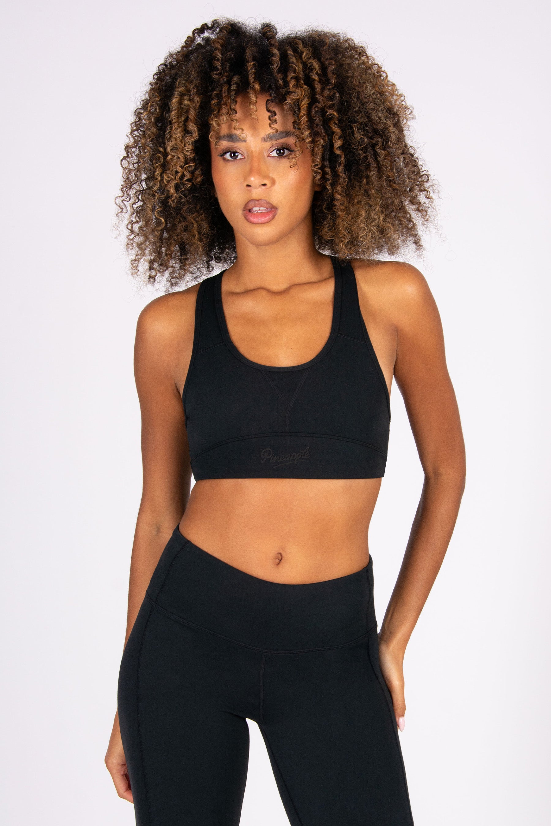 Woman wearing a black sports bra and leggings on a white background