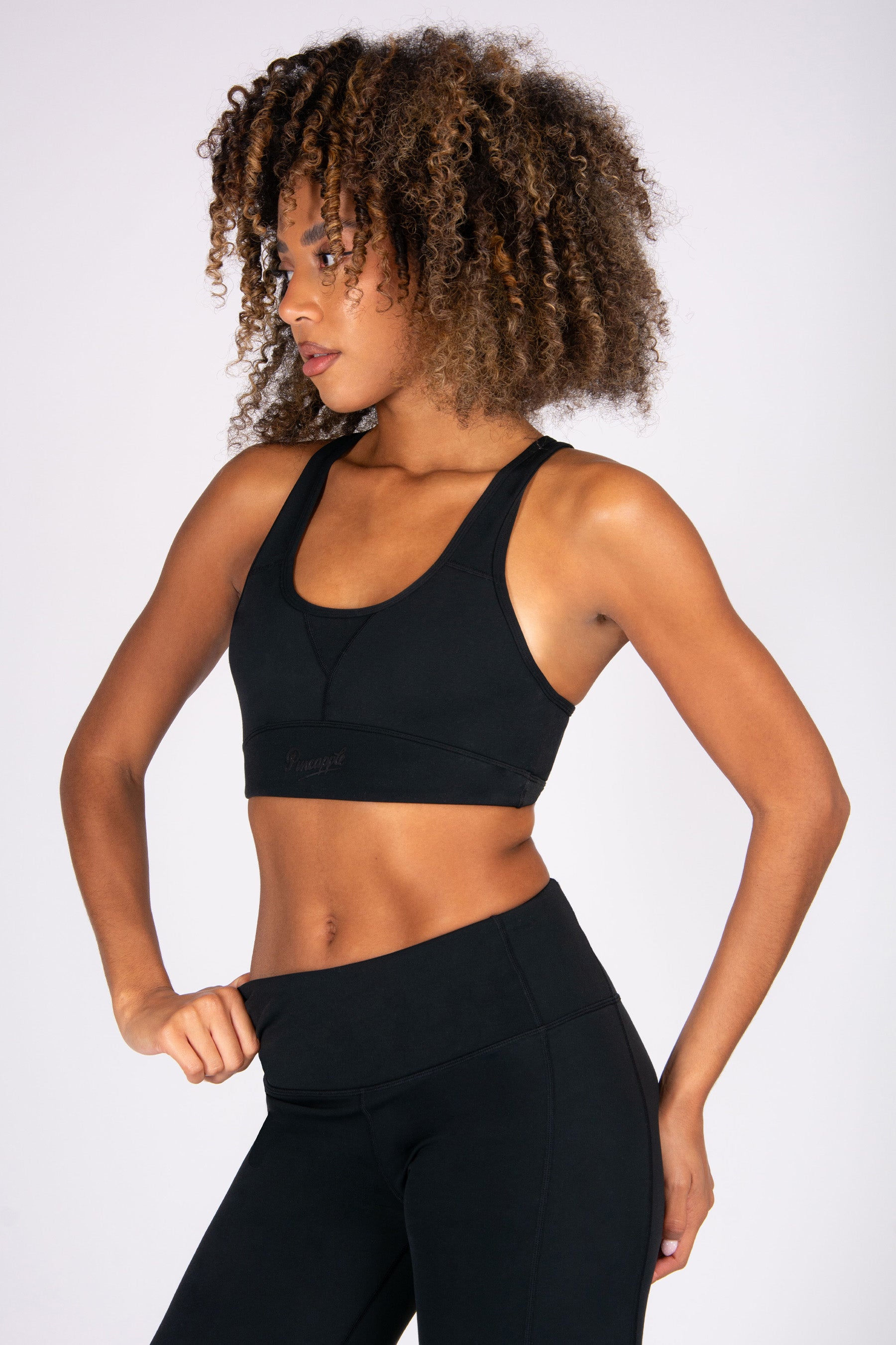 Woman wearing a black sports bra and leggings on a white background