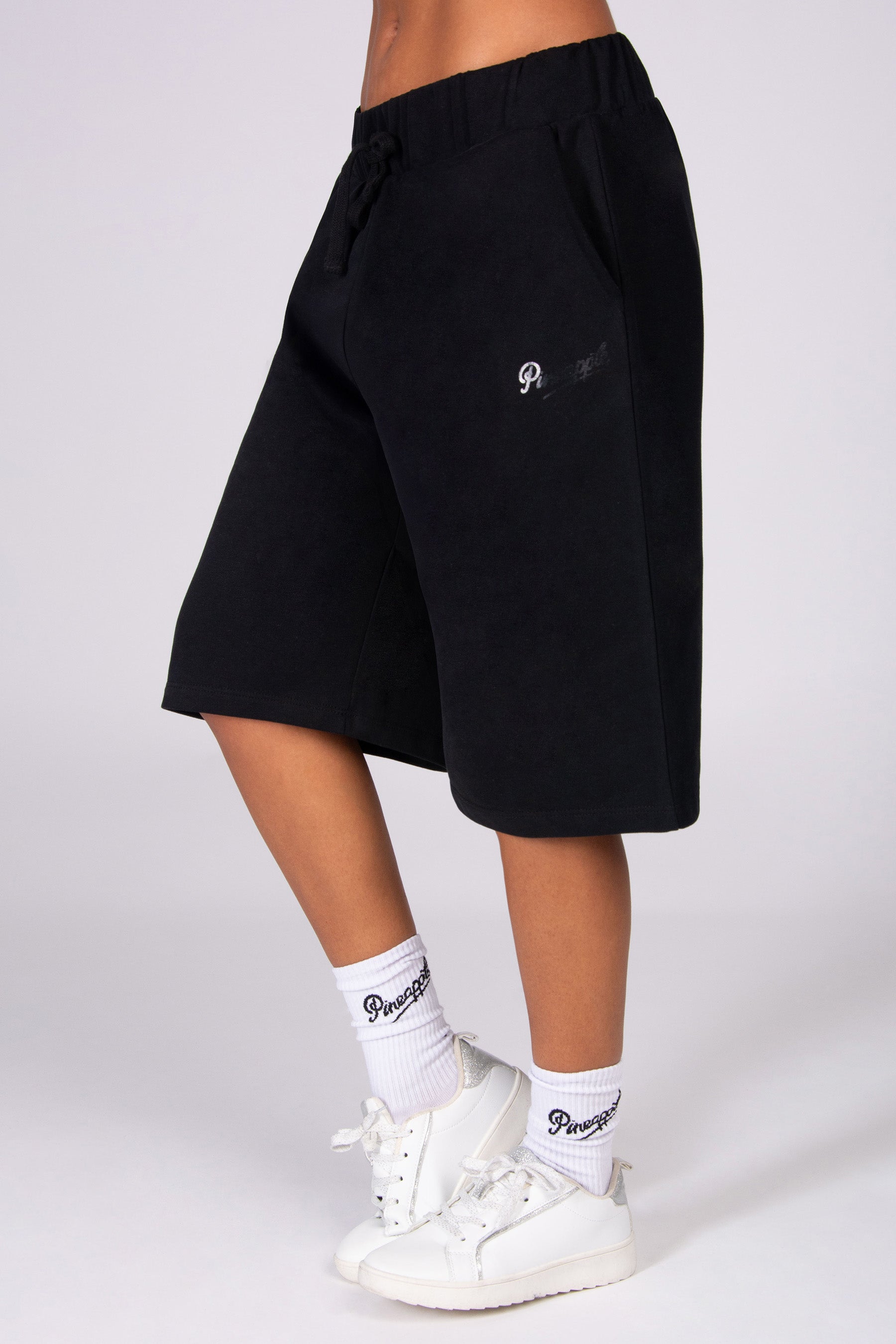 Black super oversized basketball shorts worn by a person on a white background