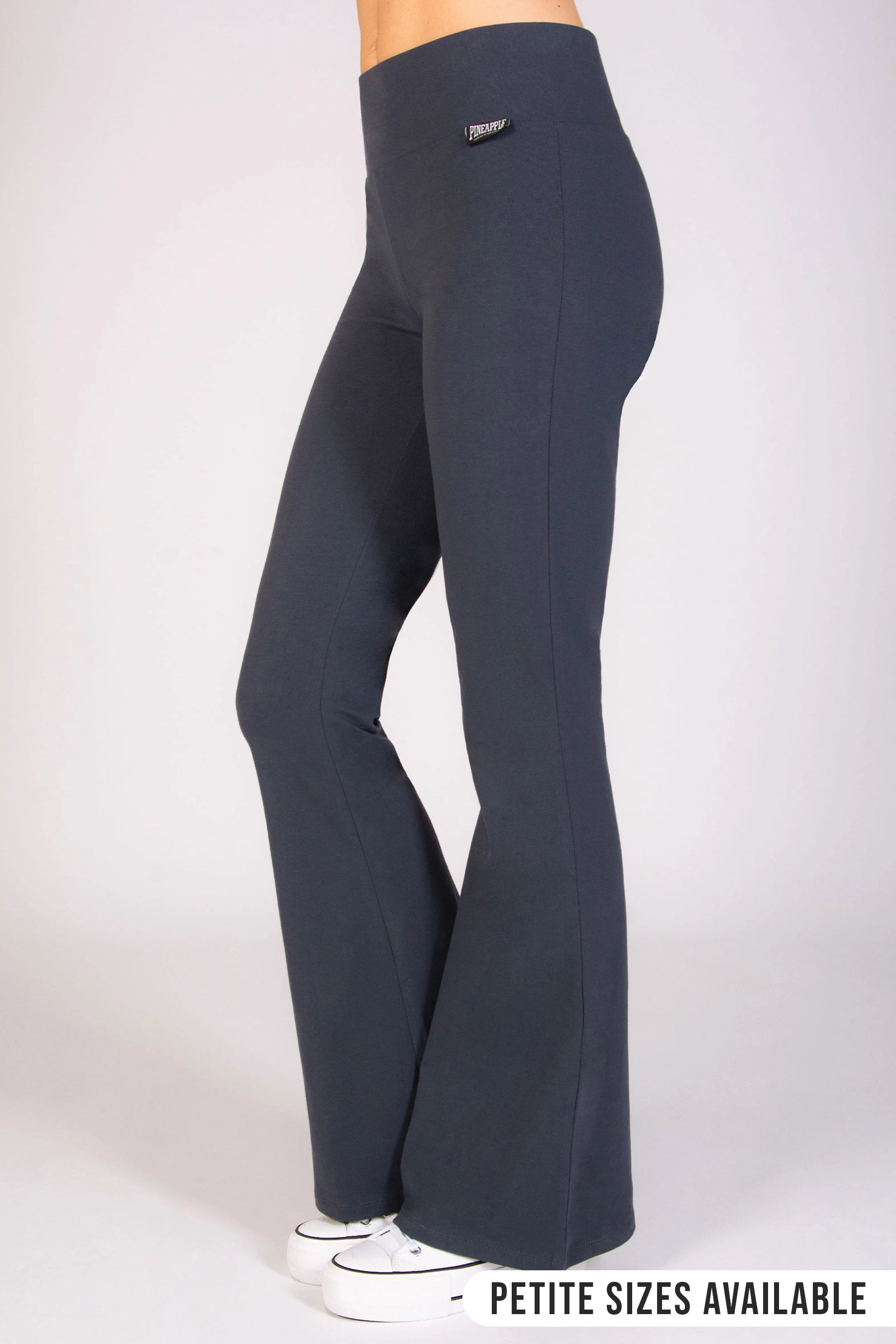 A side profile of a person wearing dark grey flared jersey trousers with an elasticated waistband, standing against a neutral background.