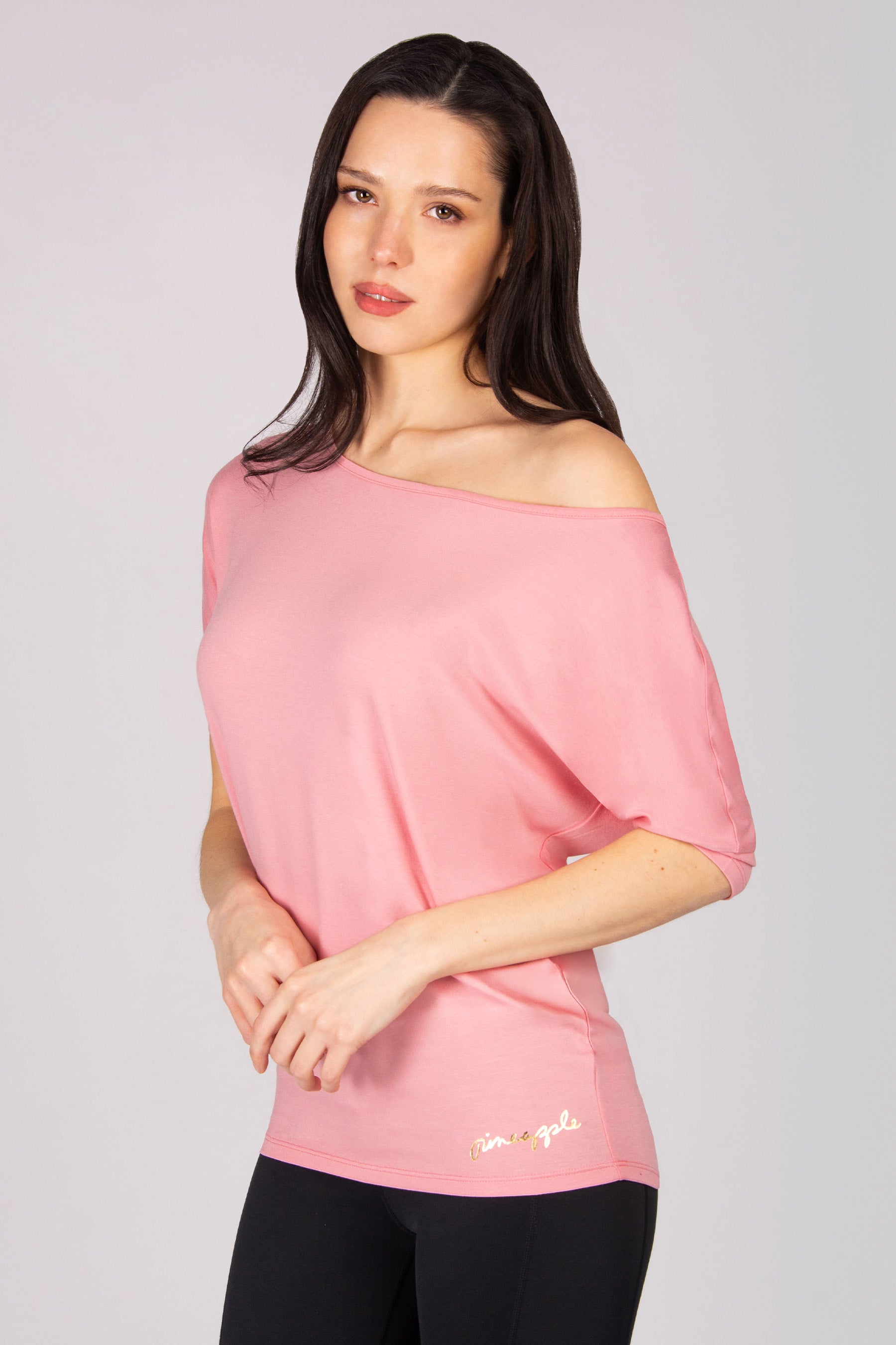 Woman wearing a pink off-shoulder top  on a plain background