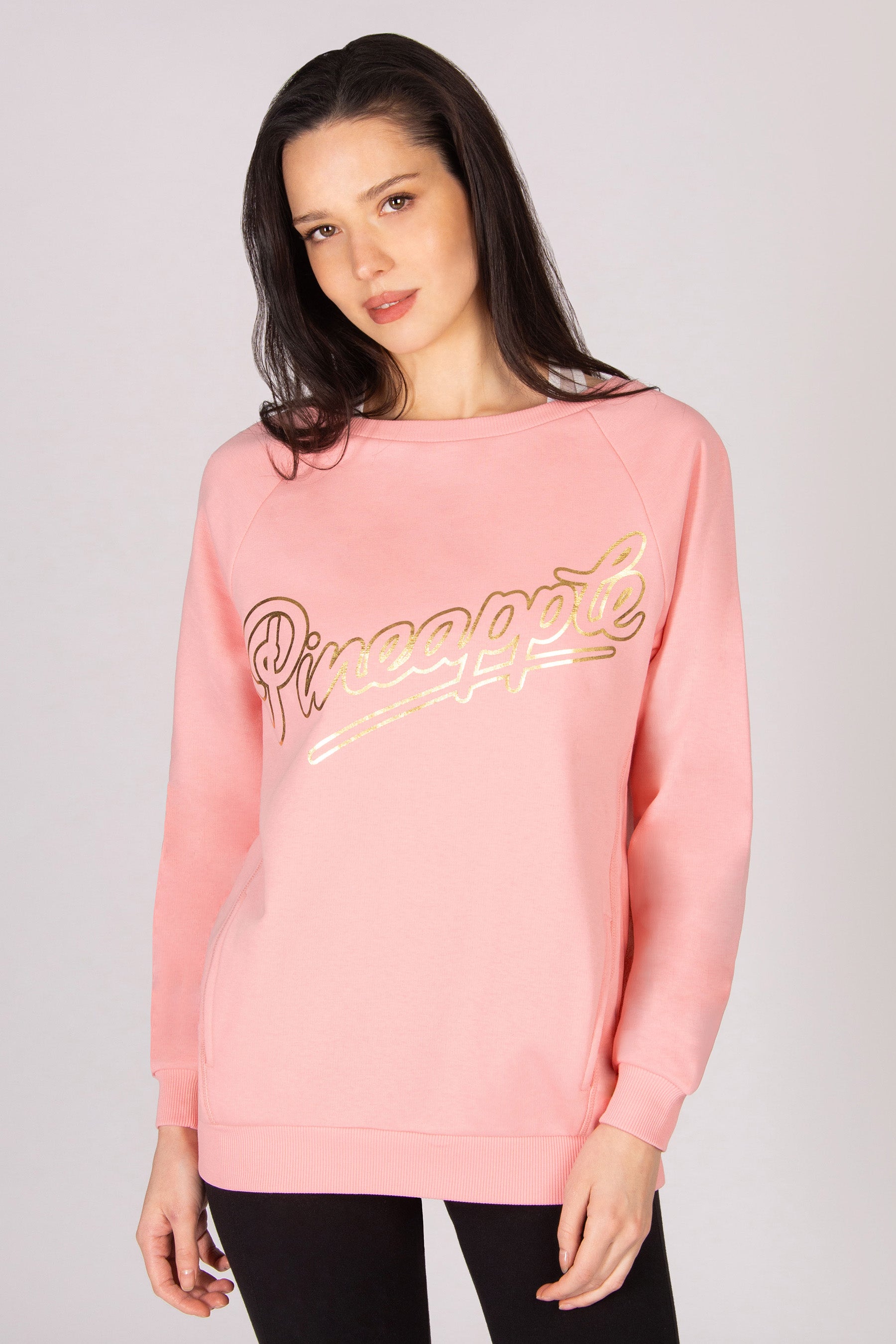 Woman wearing a coral pink sweatshirt on a plain background