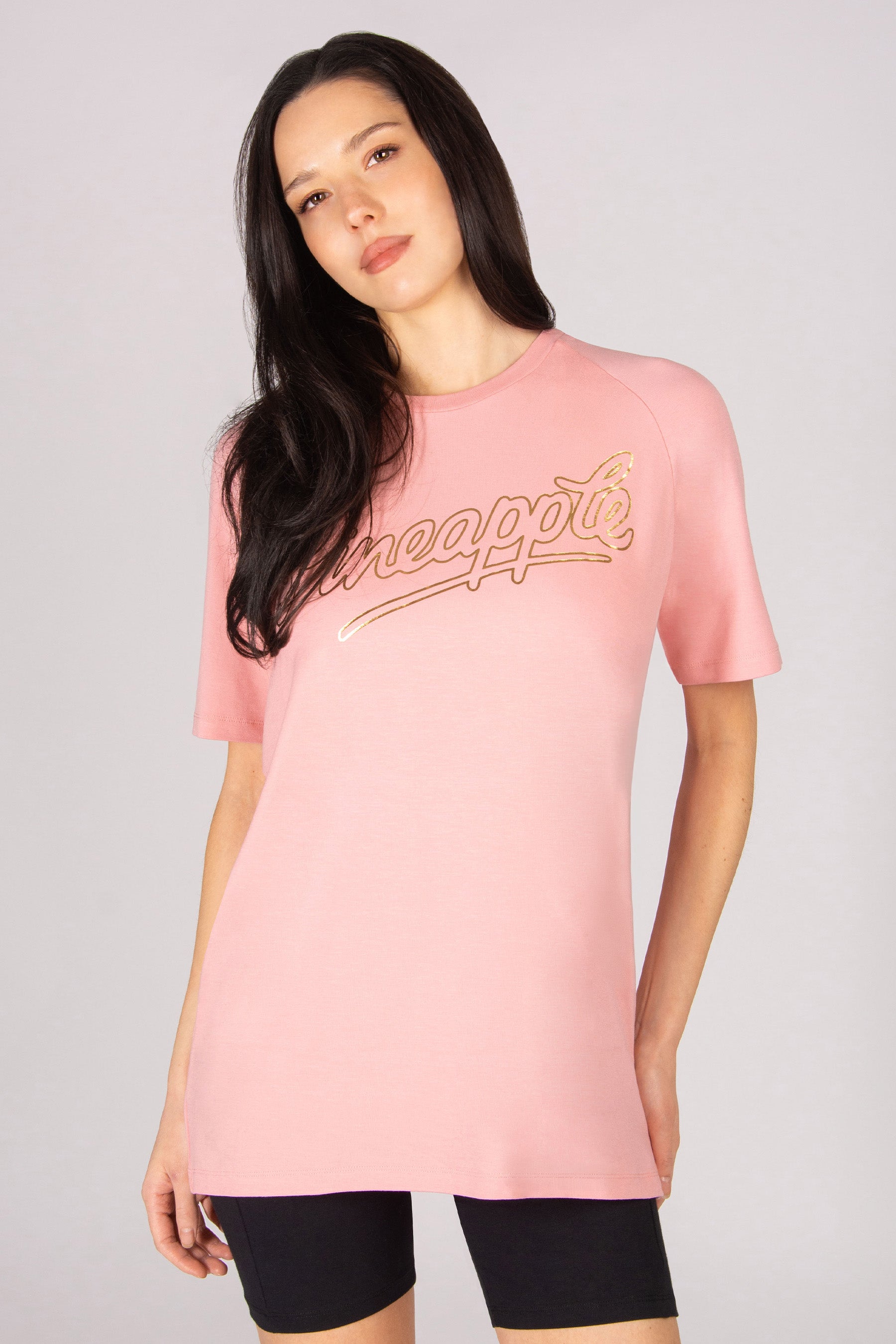 Woman wearing a coral pink oversized t-shirt on a plain background