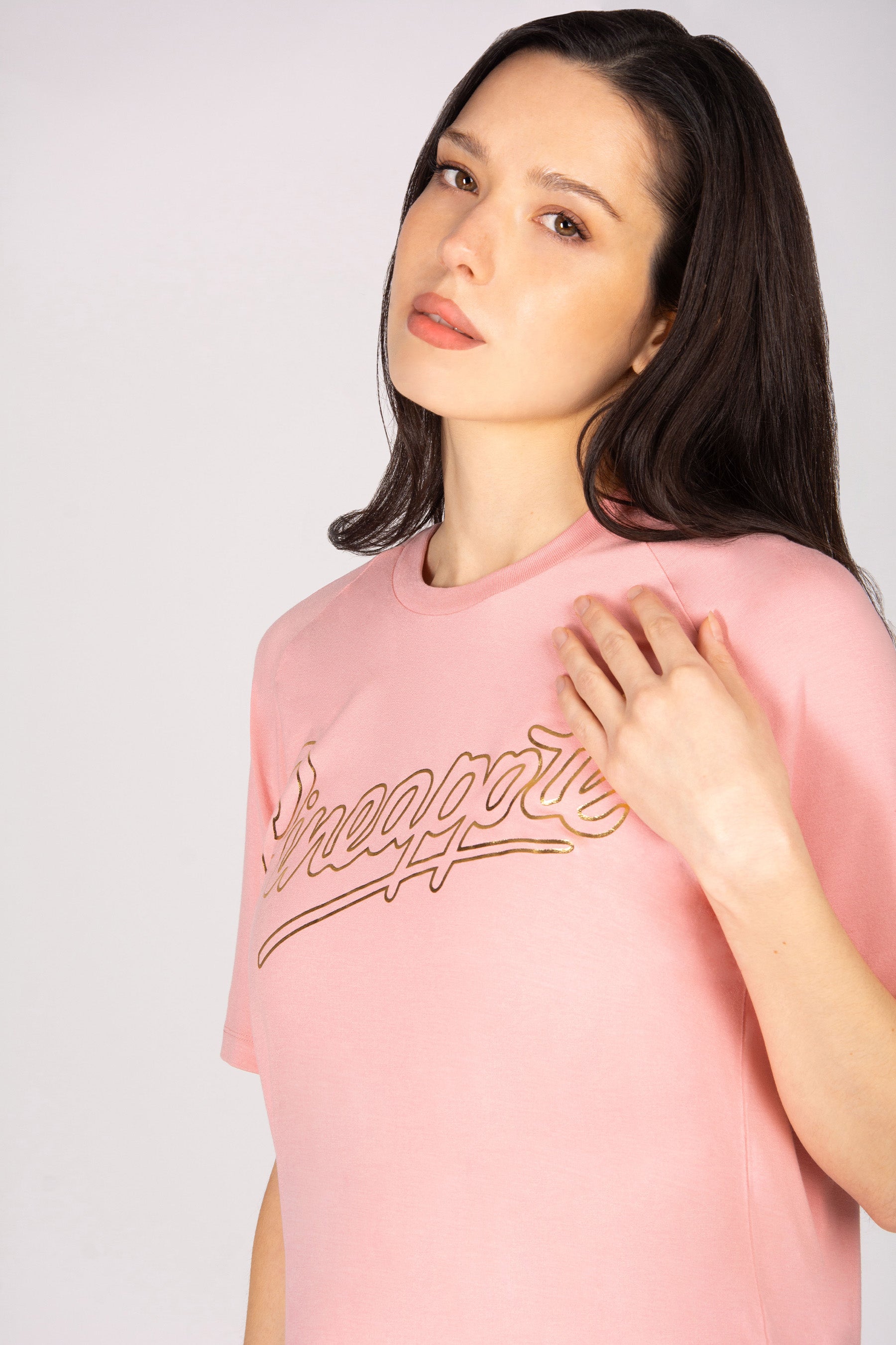 Woman wearing a coral pink t-shirt against plain background