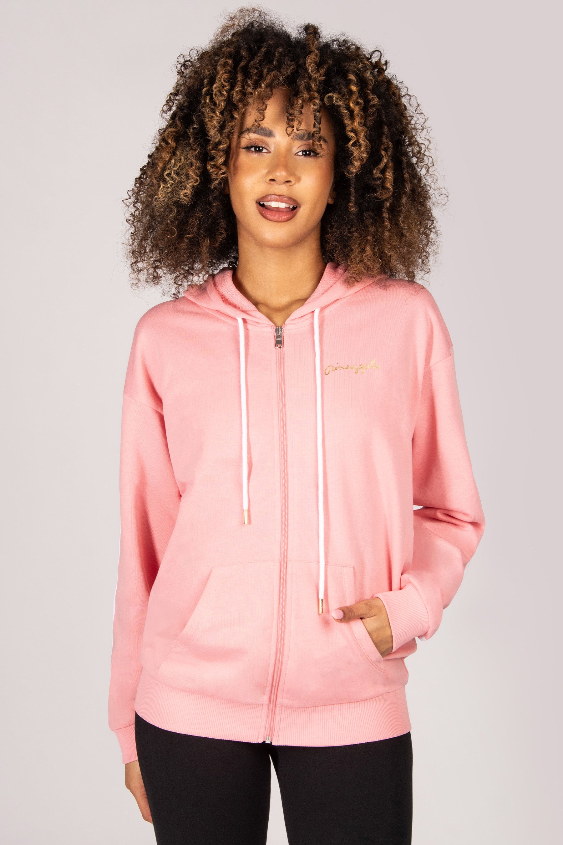 Woman wearing a light pink hoodie with full-zip against a plain background
