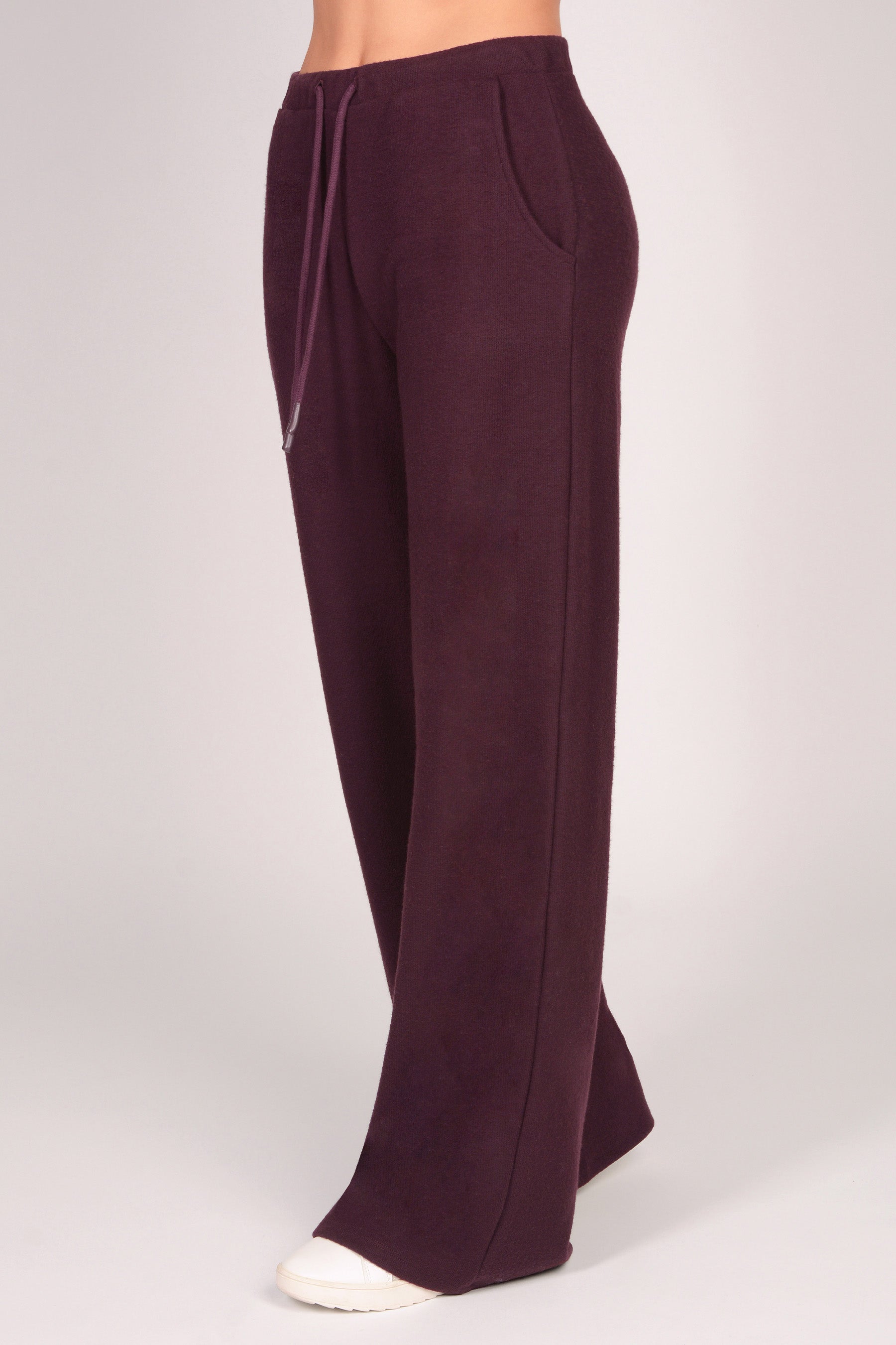 Women's maroon brown wide leg trousers with pockets and drawcord on a plain background.