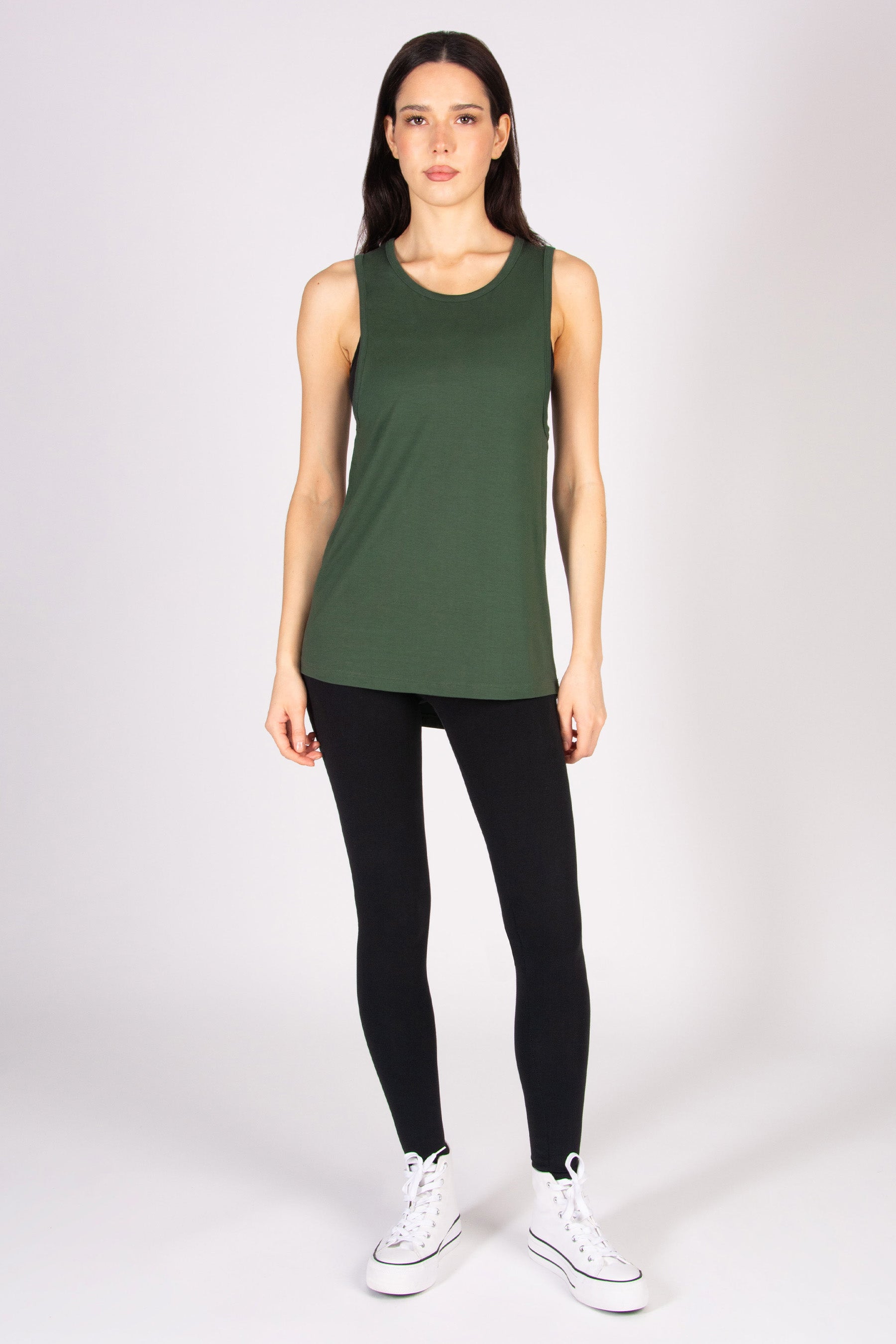 Woman wearing a khaki tank top and black leggings on a white background