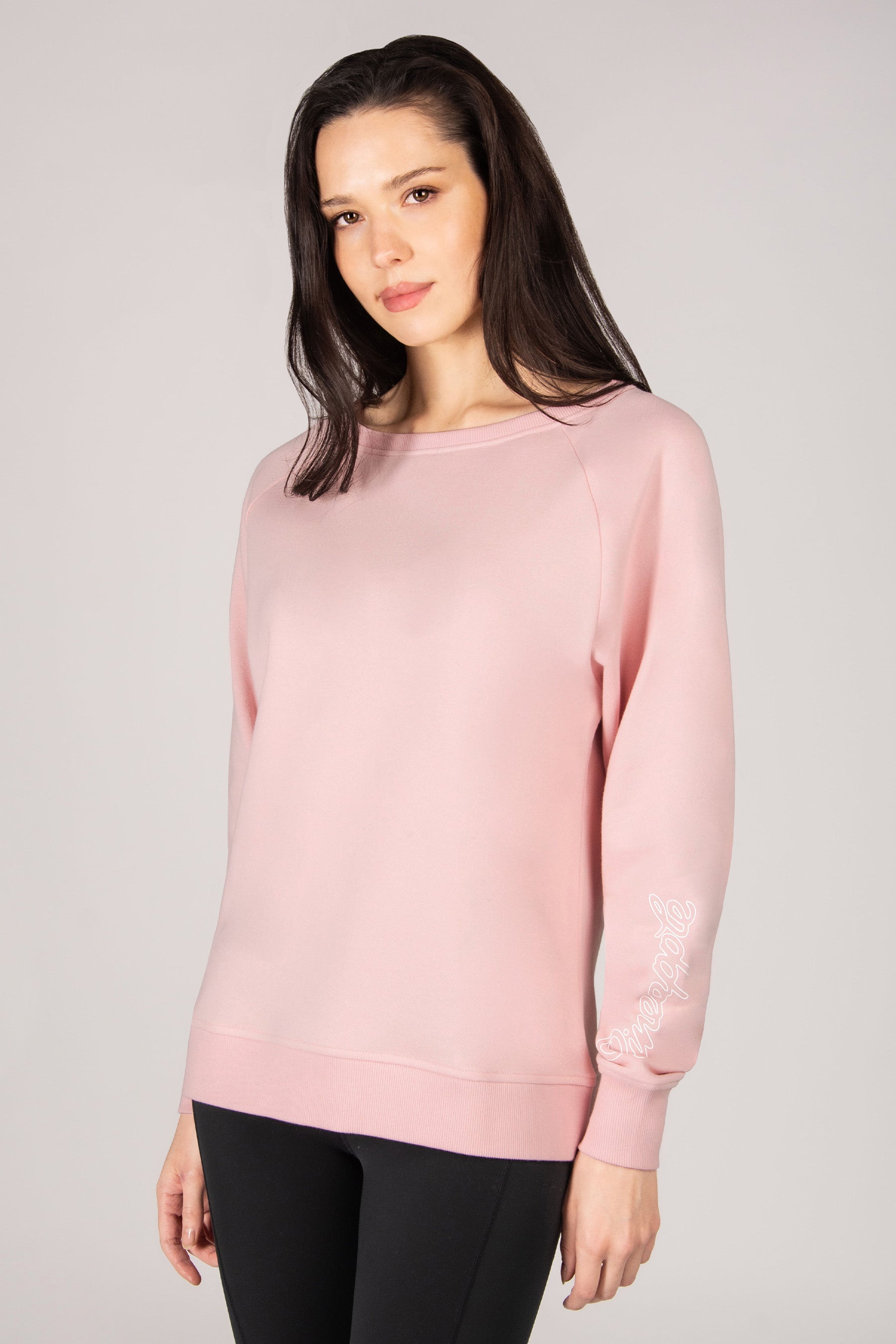 Woman wearing a light pink sweatshirt against a plain background