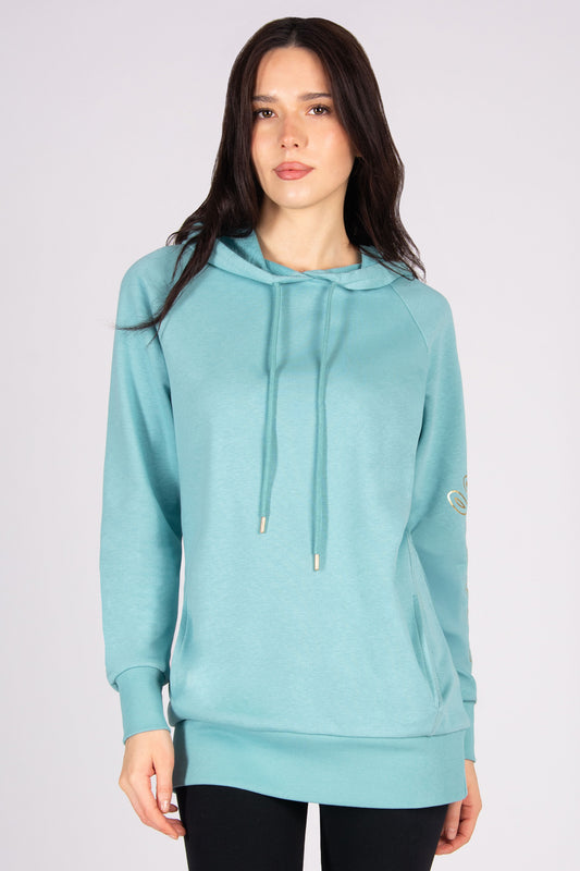 Woman wearing a light blue longline hoodie and black leggings against a plain background