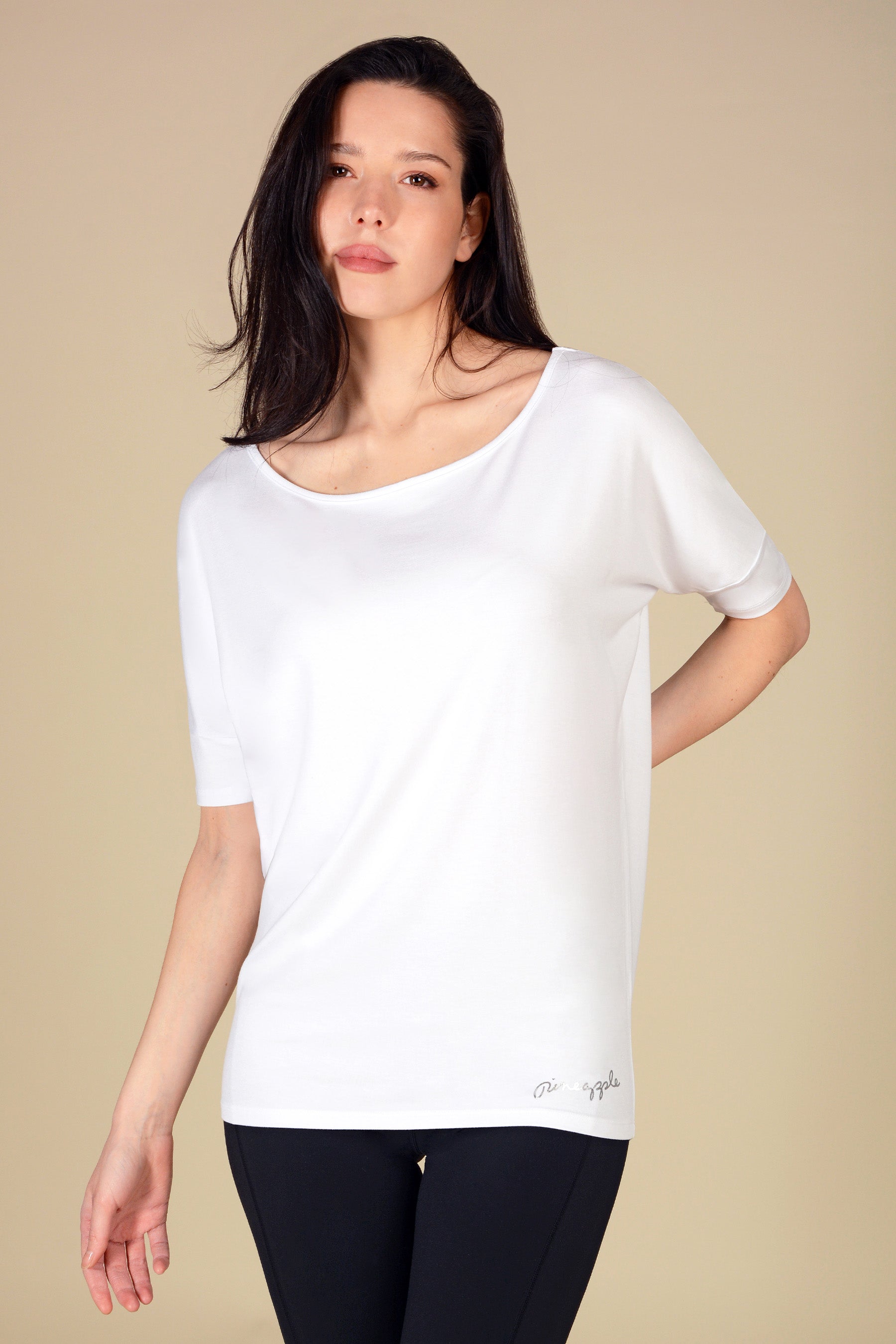 Woman wearing a white short sleeve tunic top against a beige background