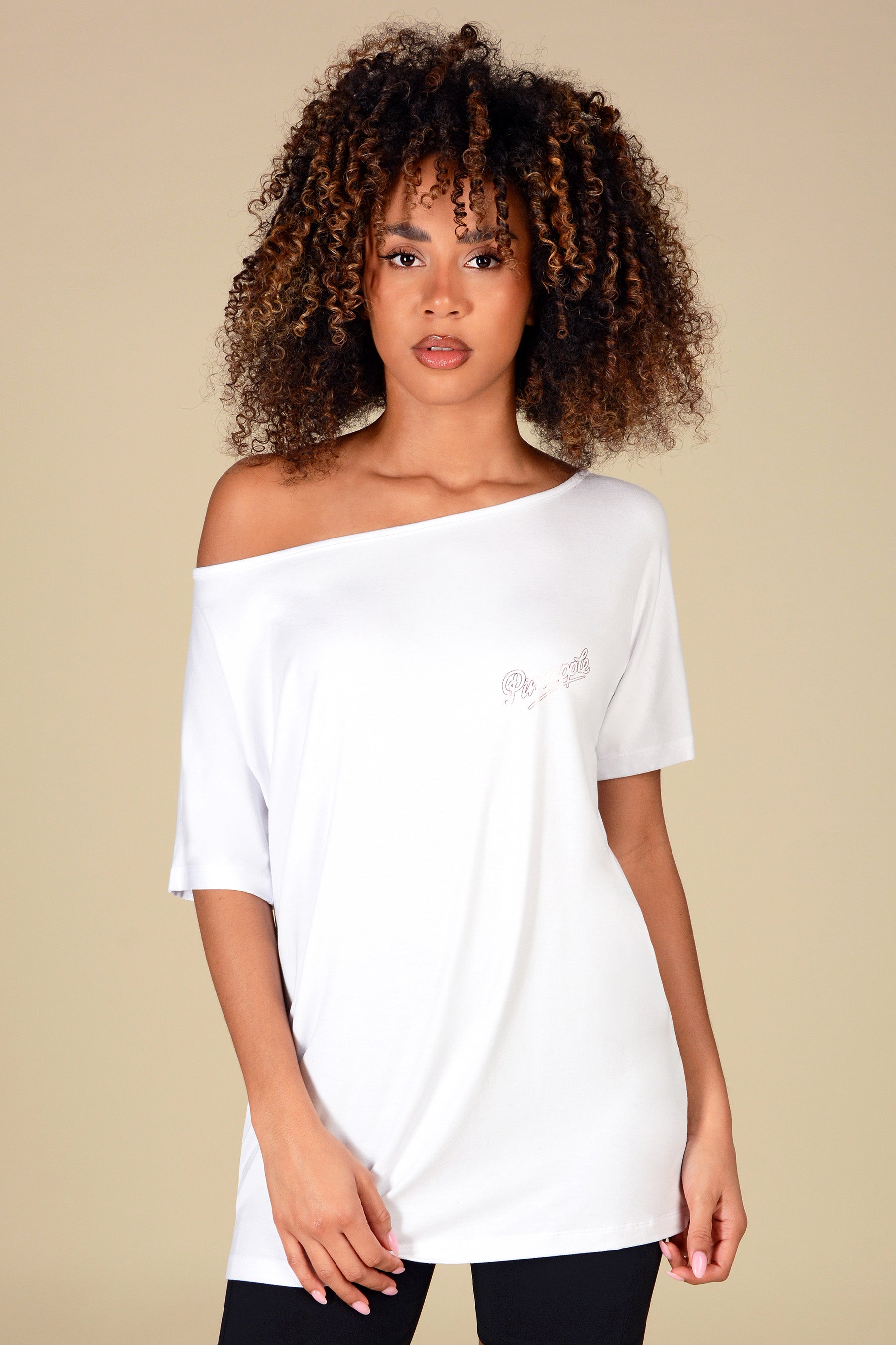 Woman wearing a white off-shoulder top with a brand logo on a beige background