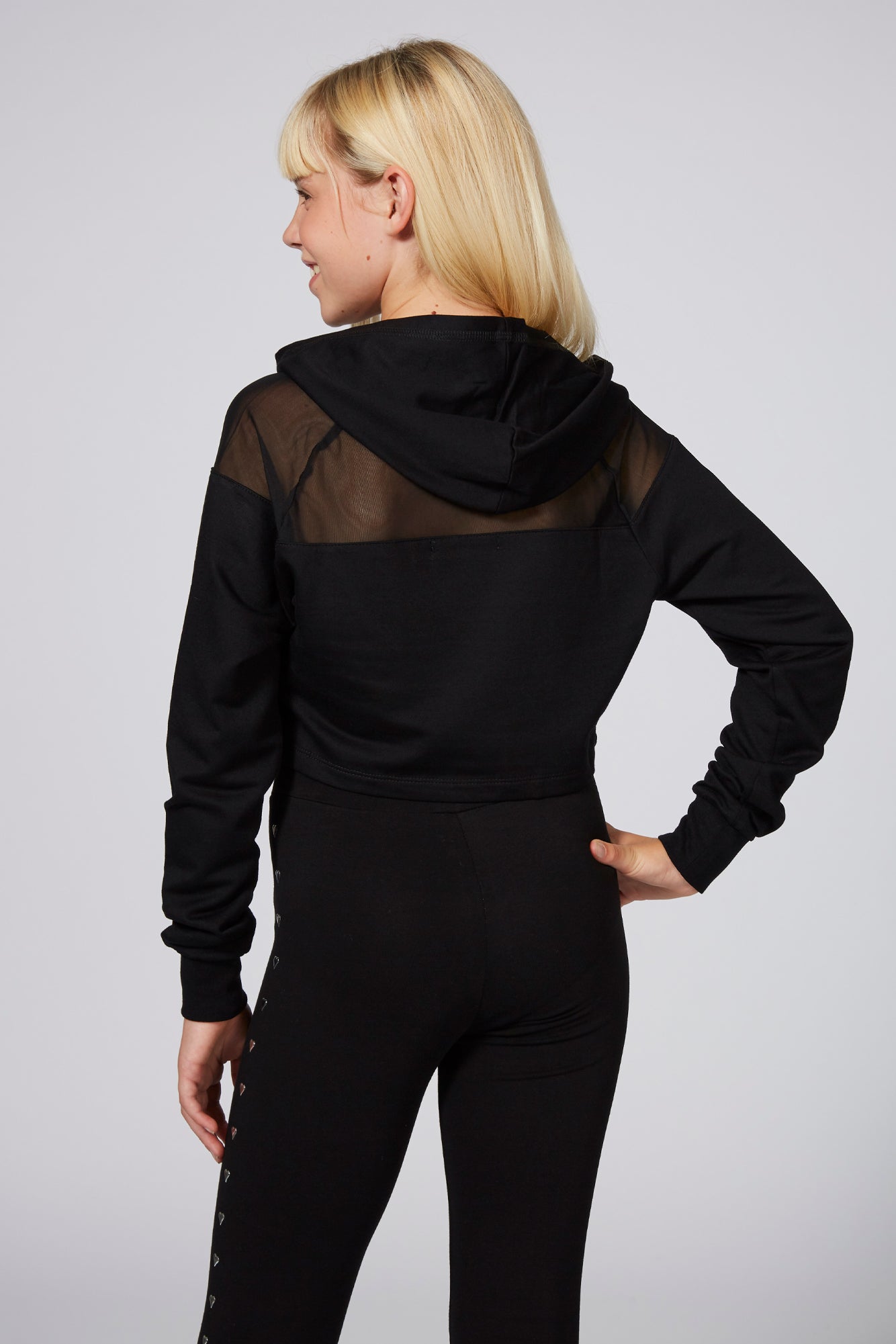 Girl wearing Black Mesh Panel Crop Hoodie and black Heart Stud Leggings